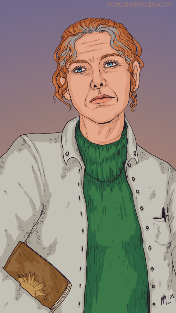 Maureen Monaghan Portrait of an older woman with greying red hair in a bun, blue eyes, and light skin, wearing a green sweater and a labcoat.